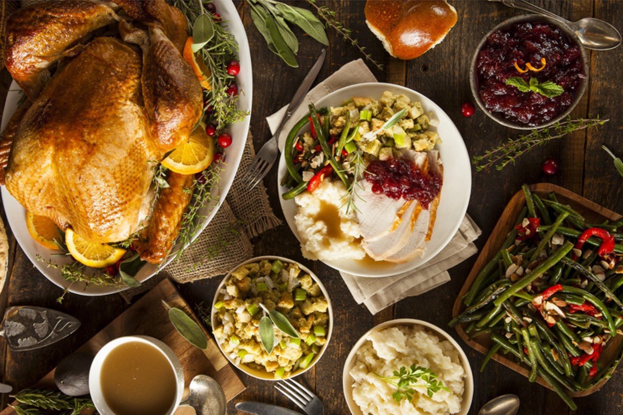 Thanksgiving turkey roasting in the oven with a full holiday dinner spread prepared using SALTOPIA seasonings